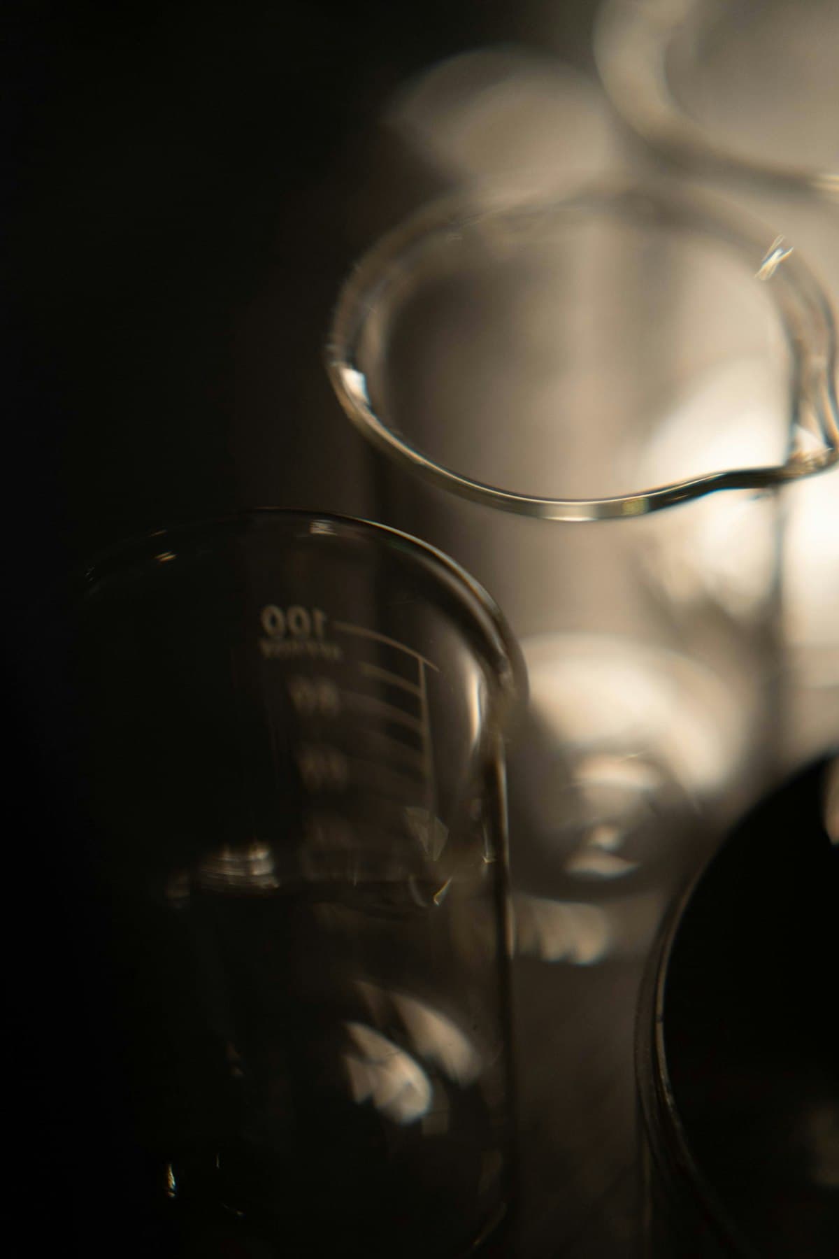 Glass beakers catching the light against a dark background