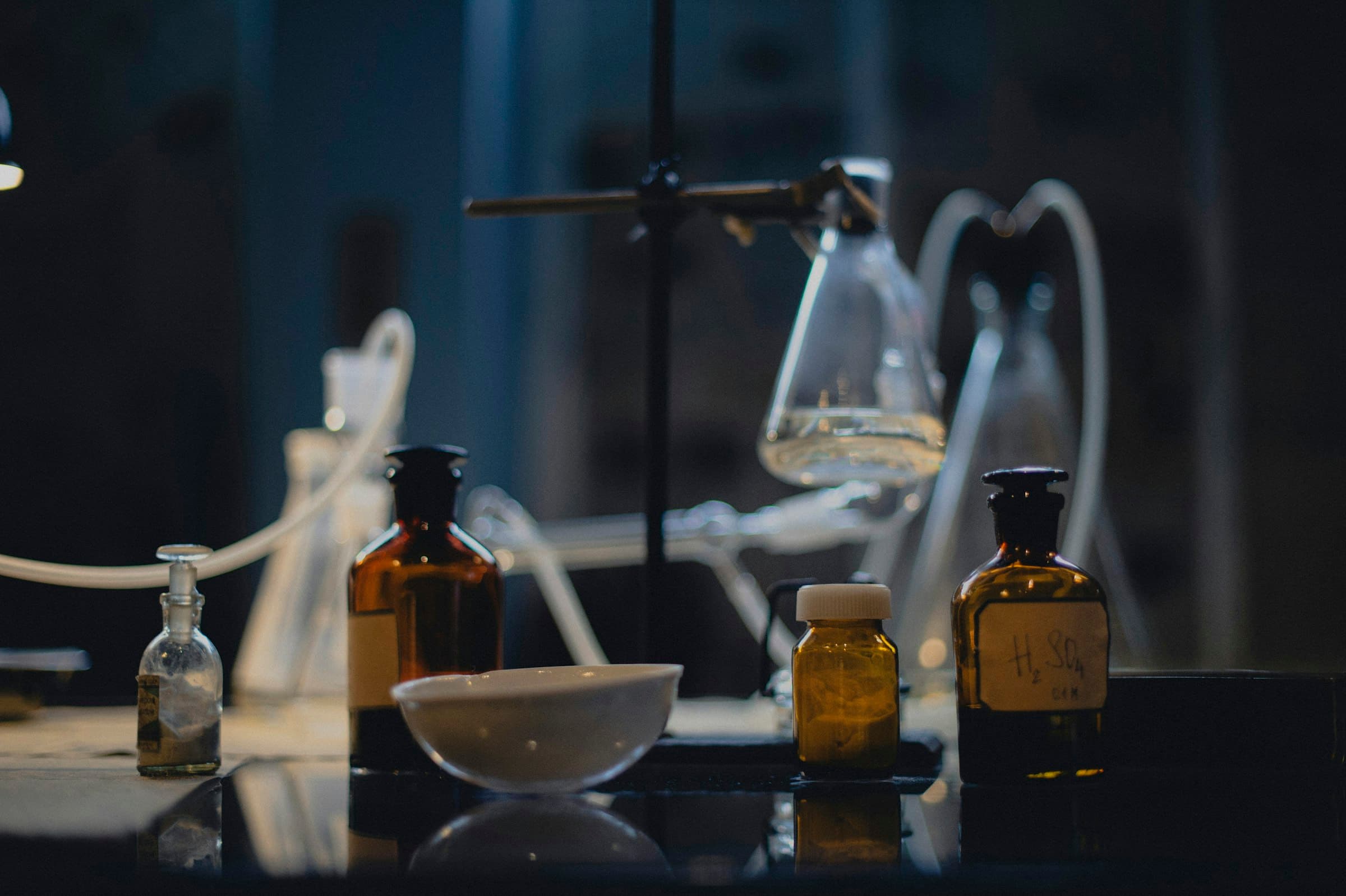 Laboratory glassware and amber reagent bottles on a dark bench
